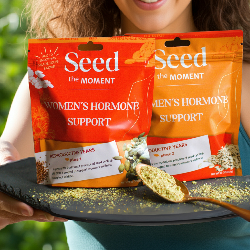 Two packages of 'Seed the Moment Women's Hormone Support' on a tray with a spoonful of product.