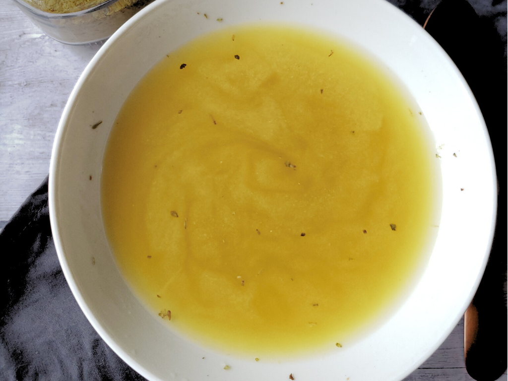 White bowl filled with vegetable broth on a dark surface