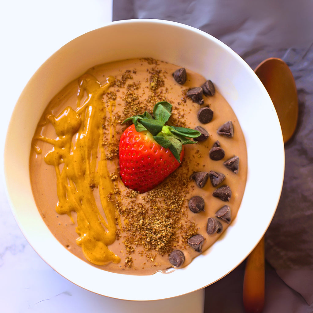 a smoothie bowl with strawberry, chocolate chips, and drizzle on a marble surface