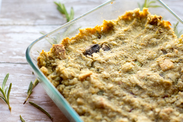 Baked dish in a glass casserole dish with rosemary on a wooden surface